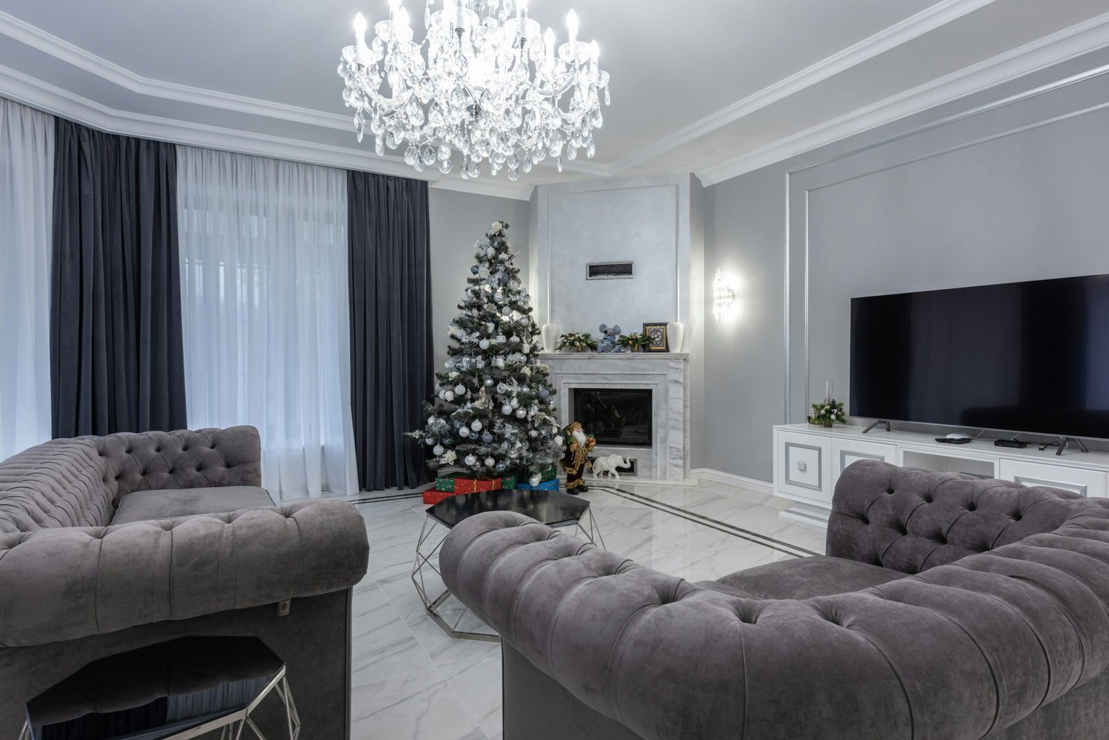 Luxurious living room with Christmas tree, chandelier, and fireplace.